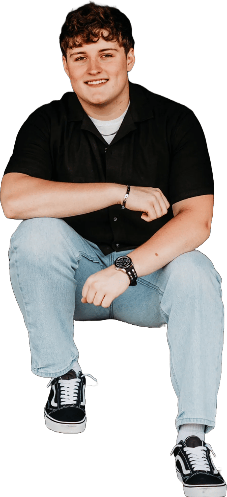 Morgan Stovold, sitting and smiling, in a black short-sleeve shirt and light jeans
